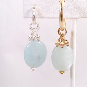Könnte beinhalten: Ein Paar Creolen mit einem ovalen Anhänger aus hellblauem Edelstein. Die Ohrringe sind aus Gold und Silber.
