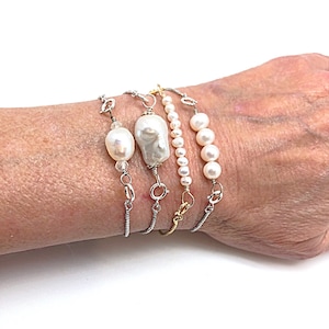 May include: Four pearl bracelets with silver and gold chains. The bracelets feature white pearls and a large baroque pearl.
