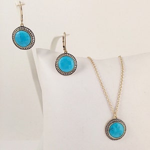 May include: A turquoise and gold necklace and earrings set with a round pendant and matching earrings. The pendant and earrings are surrounded by a halo of small diamonds.