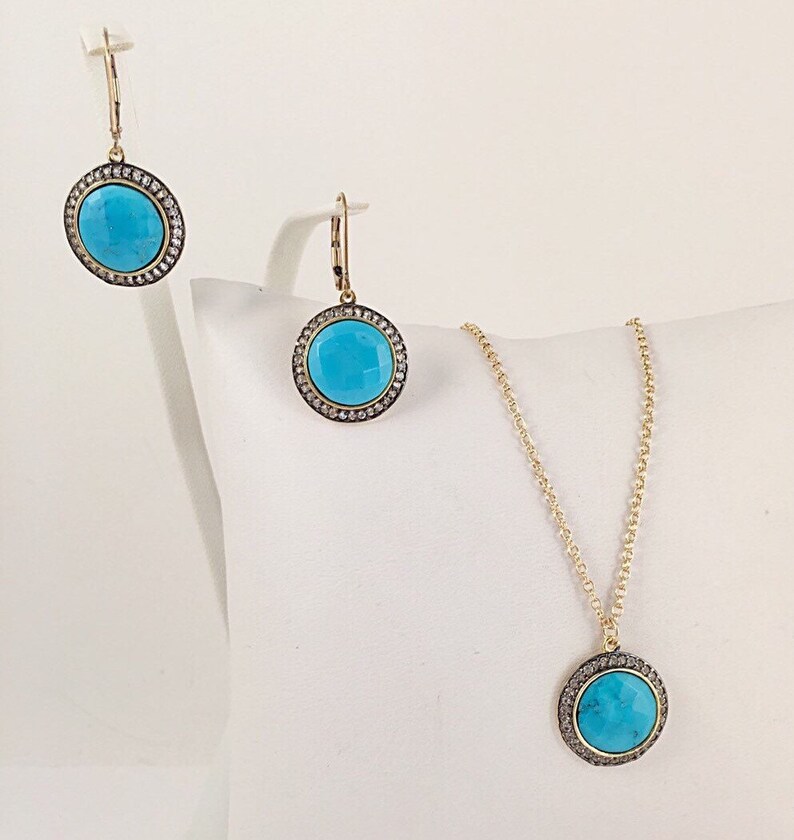 May include: A turquoise and gold necklace and earrings set with a round pendant and matching earrings. The pendant and earrings are surrounded by a halo of small diamonds.
