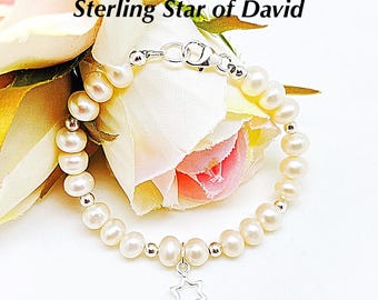 May include: A white freshwater pearl bracelet with a sterling silver Star of David charm.