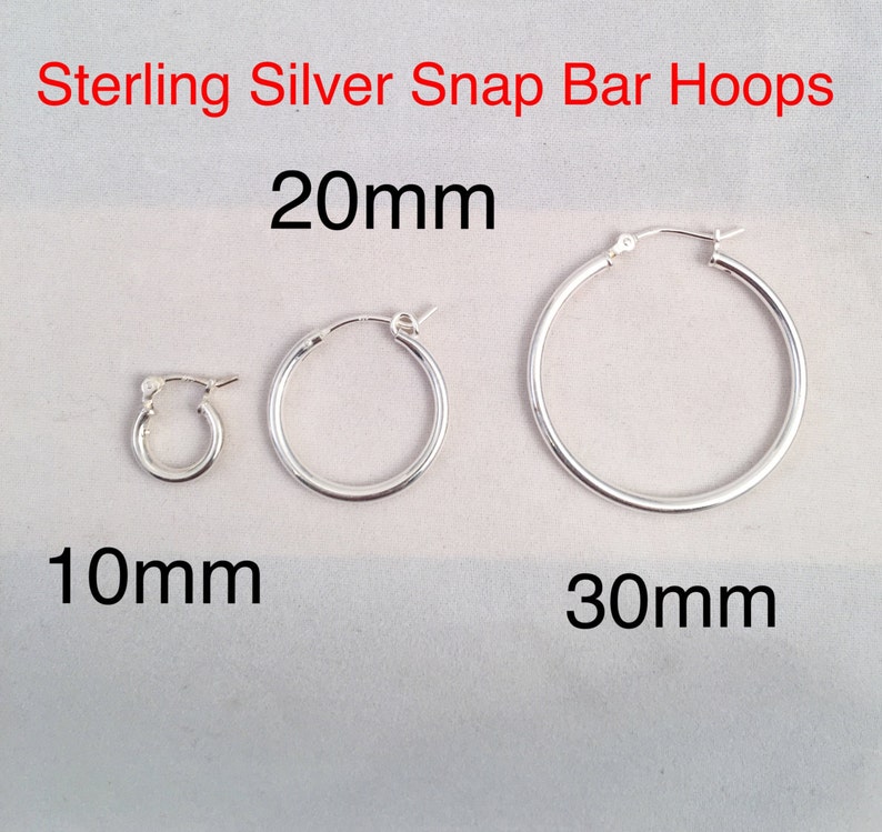 May include: Three sterling silver snap bar hoops in different sizes: 10mm, 20mm, and 30mm. The hoops are all silver and have a smooth finish.