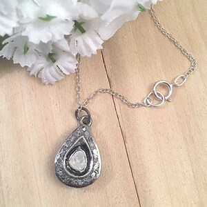 Puede incluir: Un collar de cadena de plata con un colgante en forma de l&aacute;grima que presenta un gran diamante en bruto rodeado de diamantes m&aacute;s peque&ntilde;os.