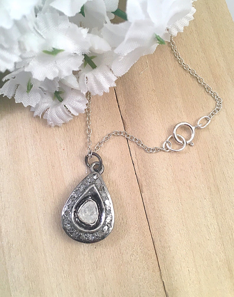 Puede incluir: Un collar de cadena de plata con un colgante en forma de l&aacute;grima que presenta un gran diamante en bruto rodeado de diamantes m&aacute;s peque&ntilde;os.