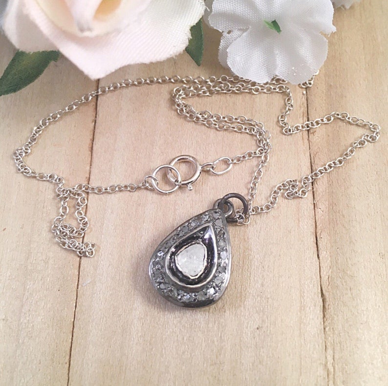 Puede incluir: Un collar de cadena de plata con un colgante en forma de l&aacute;grima que presenta un diamante blanco rodeado de diamantes m&aacute;s peque&ntilde;os.