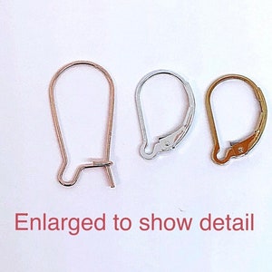 May include: Three earring hooks in different finishes: gold, silver, and rose gold. The hooks are enlarged to show detail.
