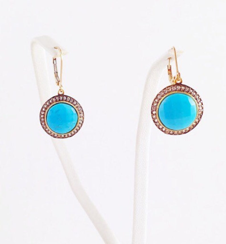 May include: A pair of gold earrings with turquoise stones and a diamond halo setting.