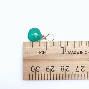 May include: A green gemstone pendant with a gold wire wrap. The pendant is approximately 1/2 inch in size.