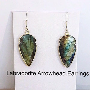 May include: A pair of gold-toned earrings with labradorite arrowhead-shaped stones. Labradorite Arrowhead Earrings.