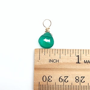 May include: A green gemstone pendant with a gold wire wrap. The pendant is approximately 1/2 inch in size.