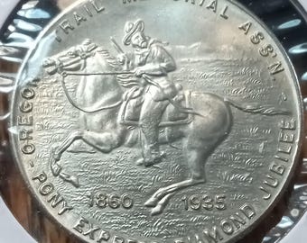 Op de afbeelding: Een zilveren munt ter herdenking van de Oregon Pony Express Diamond Jubilee. De munt toont een ruiter te paard, met tekst waaronder "Oregon Pony Express Diamond Jubilee" en de jaren 1860 en 1935. De munt zit in een beschermende houder.
