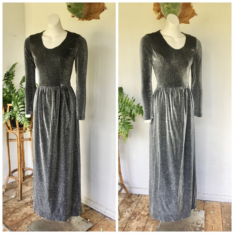 May include: A long-sleeved silver and black sparkly dress with a round neckline. The dress has a fitted bodice and a flowing skirt.