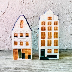 Puede incluir: Dos casas de cerámica blanca con bordes azules y ventanas naranjas. Las casas están decoradas con un patrón de waffle.