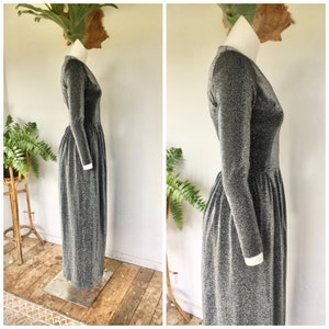 May include: A long-sleeved silver and black glitter dress with a V-neckline. The dress has a gathered waist and a flowing skirt.