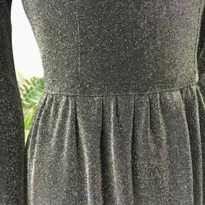 May include: A black dress with a sparkly silver texture. The dress has a fitted bodice and a flowing skirt.