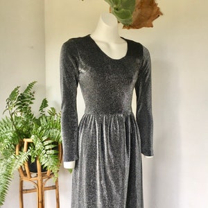 May include: A silver and black long-sleeved maxi dress with a scoop neck and a gathered waist.