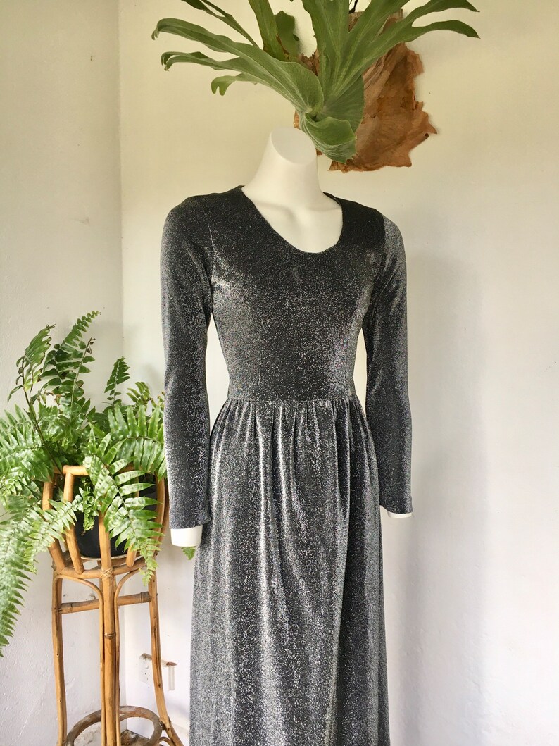 May include: A silver and black long-sleeved maxi dress with a scoop neck and a gathered waist.
