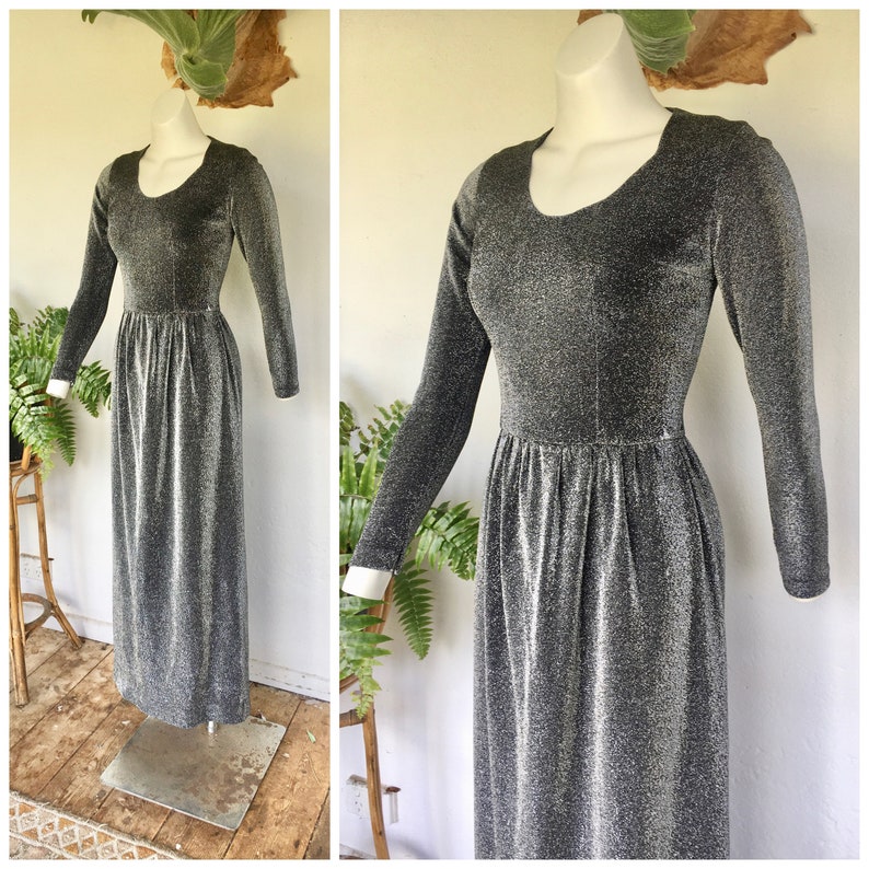 May include: A silver and black long-sleeved maxi dress with a scoop neck and a gathered waist.