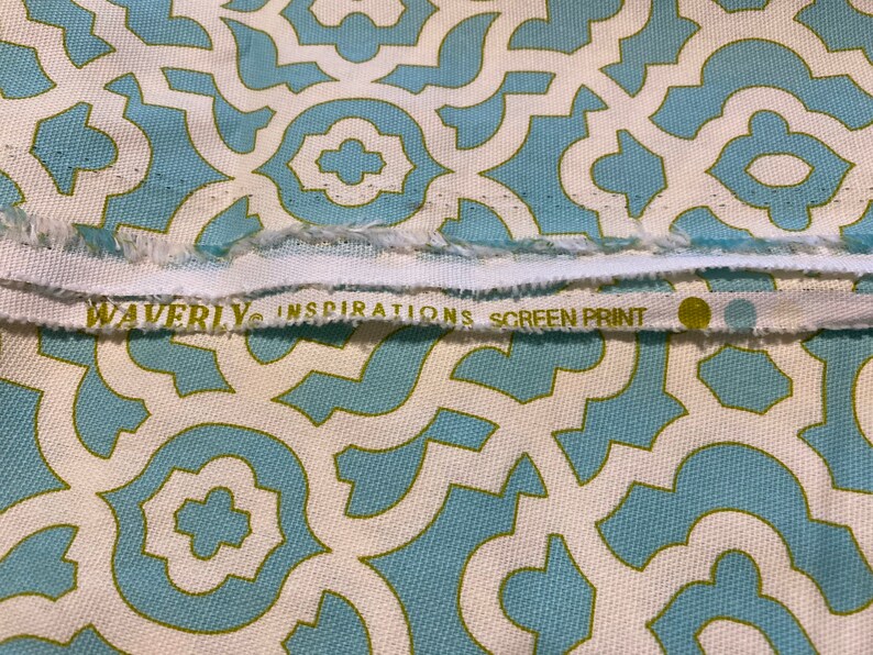 May include: White fabric with a blue and green geometric pattern. The fabric has a label that reads "Waverly Inspirations Screen Print".