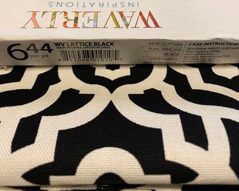 May include: A close-up of black and white fabric with a geometric pattern. The fabric is labeled "WV Lattice Black" and has a care instruction label with details about washing and drying. The fabric is 54 inches (127 cm) wide and 9 yards (822 cm) long.