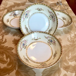 May include: Set of four white porcelain bowls with a gold rim and floral pattern. The bowls have a scalloped edge and are perfect for serving soup, cereal, or dessert.