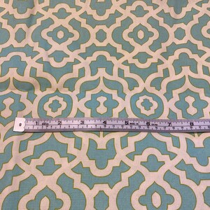May include: A close-up of a fabric with a repeating geometric pattern. The pattern is made up of light blue and white shapes on a cream background. A ruler is visible at the bottom of the image.
