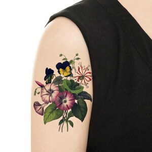 Puede incluir: Un tatuaje temporal con un ramo de flores de estilo vintage en tonos rosa, morado, amarillo y verde.