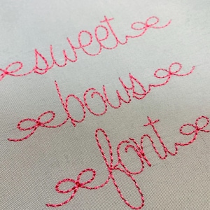 May include: Pink embroidered text on a white fabric background. The text reads "sweet house of fonts".