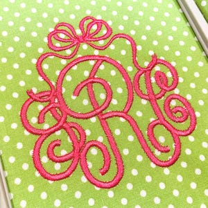 May include: A bright lime green fabric featuring a repeating white polka dot pattern. Centered on the fabric is a hot pink embroidered monogram of the letter R, designed with intricate swirling flourishes and a bow detail at the top.