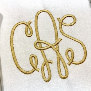 May include: A white fabric surface featuring a centered, gold-colored embroidered monogram consisting of the letters C, A, and S in a cursive, looping script style. The embroidery has a raised, textured appearance against the plain white textile.