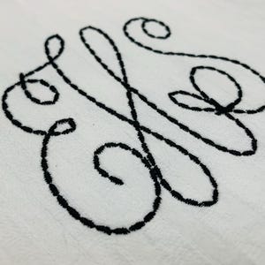 May include: A black embroidered monogram in a cursive script style. The monogram is on a white background.