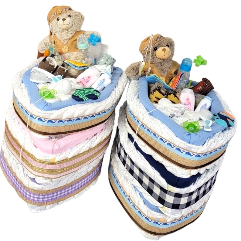 May include: Two diaper cakes, one in pink and one in blue, decorated with teddy bears, baby bottles, and other baby items.
