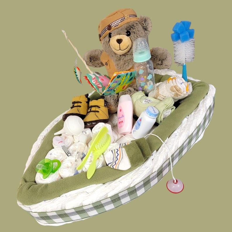 May include: A diaper cake shaped like a boat with a teddy bear wearing a fishing vest and holding a fishing rod. The boat is filled with baby supplies, including diapers, wipes, lotion, and a bottle.