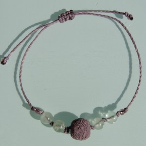 以下が含まれることがあります： グレーの紐のブレスレットに、濃いグレーのビーズと薄いグリーンのビーズが4つ付いている