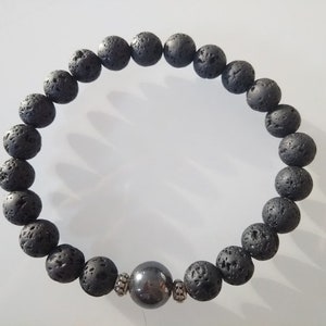 Può includere: Un braccialetto con perline di roccia lavica nera, un distanziatore argentato e una perla di ematite nera.