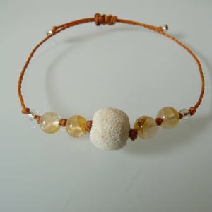 Peut inclure: Un bracelet en cordon marron avec une perle d'oursin blanche et des perles claires et ambrées.