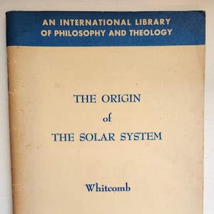 May include: A blue and cream book cover with the title "The Origin of The Solar System" by Whitcomb. The book is part of an "International Library of Philosophy and Theology" series and is labeled "Biblical and Theological Studies".