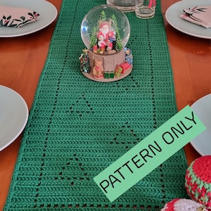 May include: Green crochet table runner with a white and red Christmas snow globe in the centre. The text "PATTERN ONLY" is written in green on a white background.