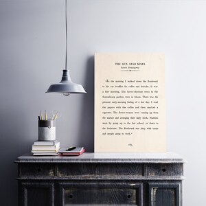 May include: A vintage book cover with the title "The Sun Also Rises" by Ernest Hemingway. The text on the cover is a passage from the book, describing a morning in Paris.