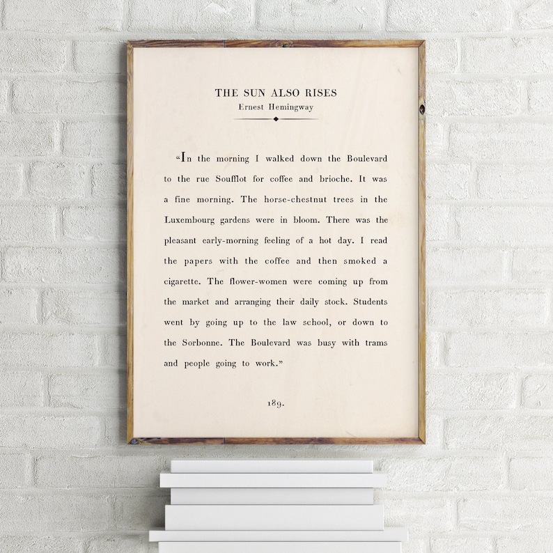 May include: A vintage book cover with a white background and black text. The title is "The Sun Also Rises" by Ernest Hemingway. The text is a quote from the book about a morning walk in Paris.