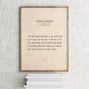 May include: A vintage-style print of a quote from Charles Dickens's "A Christmas Carol." The quote reads, "I will honour Christmas in my heart, and try to keep it all the year. I will live in the Past, the Present, and the Future. The Spirits of all Three shall strive within me. I will not shut out the lessons that they teach!" The print is on a cream-coloured background with black text.