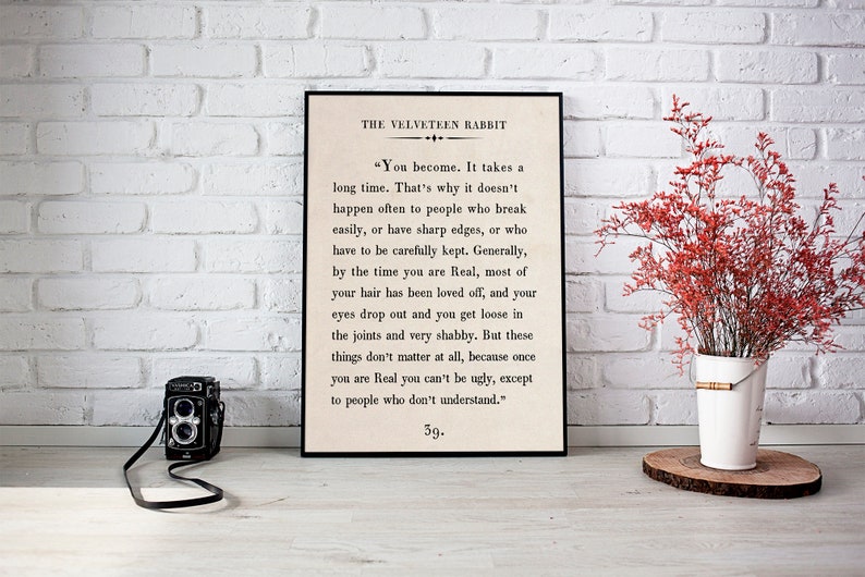 May include: A black framed print with a white background and black text. The text is an excerpt from the book "The Velveteen Rabbit" by Margery Williams. The text reads: "You become. It takes a long time. That's why it doesn't happen often to people who break easily, or have sharp edges, or who have to be carefully kept. Generally, by the time you are Real, most of your hair has been loved off, and your eyes drop out and you get loose in the joints and very shabby. But these things don't matter at all, because once you are Real you can't be ugly, except to people who don't understand." 59.
