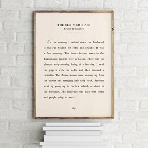 May include: A vintage book cover with the title "The Sun Also Rises" by Ernest Hemingway. The text on the cover is a passage from the book describing a morning in Paris.