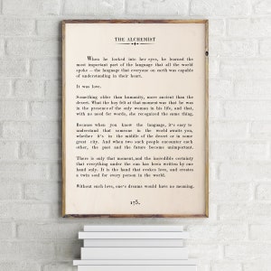May include: A vintage-style print of a page from "The Alchemist" by Paulo Coelho. The text discusses the importance of love and how it transcends language and time. The page number is 173.
