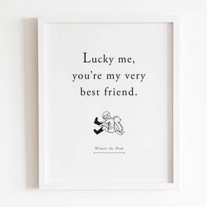 May include: A white framed print with a black and white illustration of Winnie the Pooh and Piglet. The text reads "Lucky me, you're my very best friend." and "Winnie the Pooh" at the bottom.