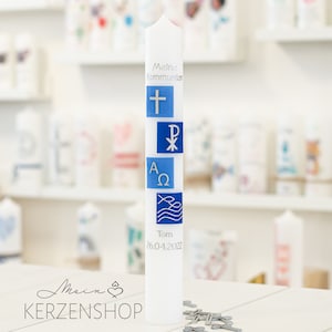 Könnte beinhalten: Weiße Kerze mit blauen und silbernen Verzierungen. Die Kerze trägt den Text "Meine Kommunion" und "Tom 26.04.2022".