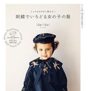 May include: A young child wearing a navy blue outfit with gold embroidery and a matching hat. The outfit features a cape-like collar adorned with gold horse designs. The image also shows a book cover with Japanese text and a design award seal.