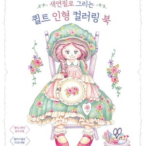 May include: A colouring book featuring a hand-drawn illustration of a doll with pink hair, wearing a green dress with pink and white flowers, sitting on a chair. The doll is holding a hoop with a floral design. The book title is "Colouring with Coloured Pencils: Quilt Doll Colouring Book".