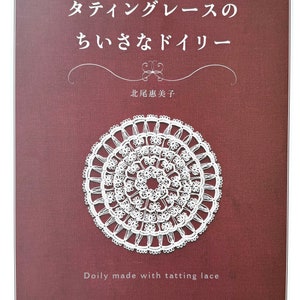 Könnte beinhalten: Ein Buchcover mit einer weißen Häkelspitze aus Tatting-Spitze auf einem burgunderfarbenen Hintergrund. Der Titel des Buches lautet "Tatting Lace Doily" auf Japanisch. Der Name des Autors lautet "Keiko Kitao" auf Japanisch. Der Text "Doily made with tatting lace" ist unter der Häkelspitze gedruckt.