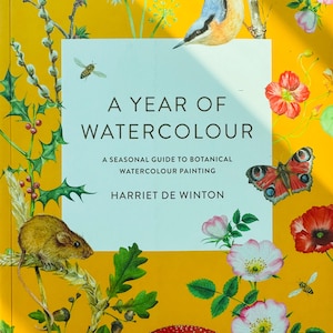 Peut inclure: Une couverture de livre avec un fond jaune et une illustration aquarelle d'une variété de plantes et d'animaux. Le titre du livre est "A Year of Watercolour: A Seasonal Guide to Botanical Watercolour Painting" par Harriet de Winton.